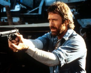 Chuck Norris points a gun in a scene from the film 'Hero And The Terror', 1988. (Photo by Cannon/Getty Images)