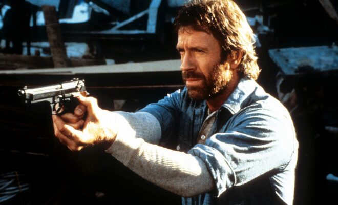Chuck Norris points a gun in a scene from the film 'Hero And The Terror', 1988. (Photo by Cannon/Getty Images)