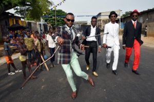 Members of La SAPE movement ("Societe des Ambianceurs et des Personnes Elegantes" or "Society of Ambiance-Makers and Elegant People") parade in a street of Abidjan on April 24, 2017 during a day of tribute to late Congolese rumba star Papa Wemba as part of the Femua festival. (Photo by Sia KAMBOU / AFP)